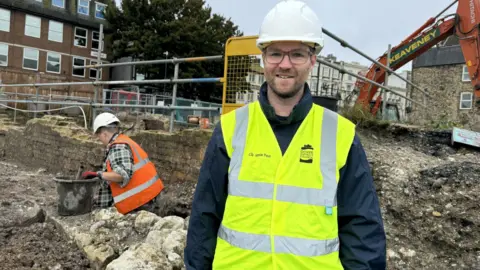 Jo Burn Jamie Pout, the deputy leader of Dover District Council, standing facing the camera wearing hi vis and hard hat
