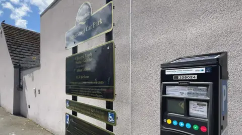 BBC/Nathan Turvey A picture of a sign for Bethel Street car park in Brighouse and a parking machine next to it. There is a white wall behind it.
