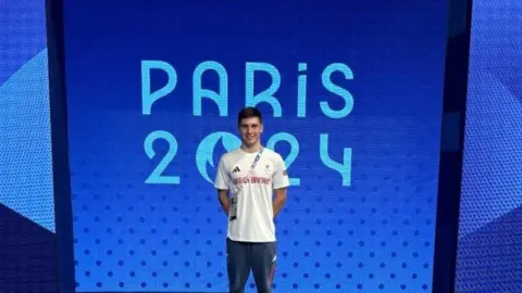 Contributed Will Ellard pictured in front of Paris 2024 Paralympic sign