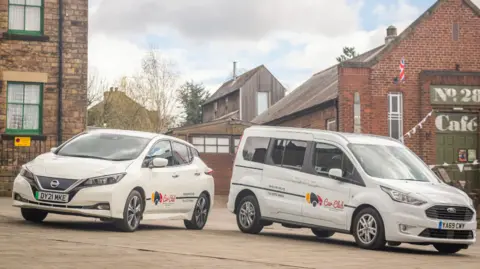 Derbyshire Community Transport One family sized car and one wheelchair friendly van with Derbyshire Community Transport logos on the side of the vehicles. 