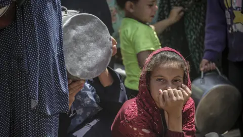 EPA A girl looks tired and worried as she hopes to receive food from a charity kitchen in Jabalia refugee camp, northern Gaza 9 May 2025