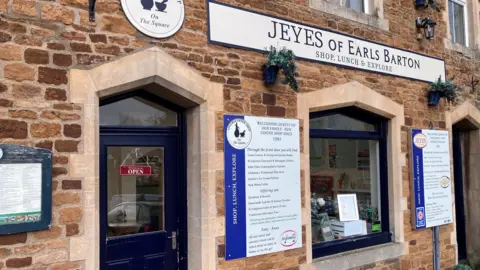 Sam Read/BBC A brick building with Jeyes of Earls Barton, shop, lunch and explore, written above a window. 