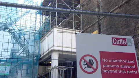 A building sign and fence warning people to say away as the structure is unsafe