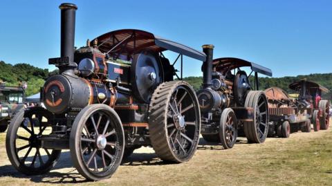 Two black and red traction engines in a row