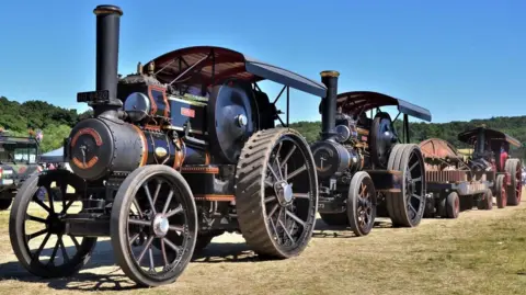 Two black and red traction engines in a row