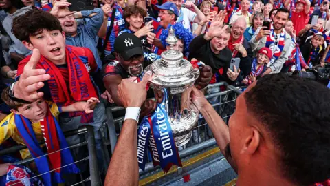 Getty Images Fans look at the FA Cup in the stadium.