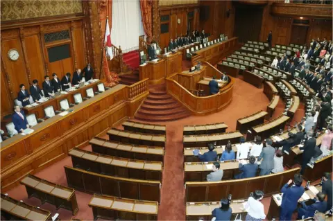 AFP/Getty Images Ruling coalition lawmakers stand to accept the anti-terror law at the upper house of parliament in Tokyo on 15 June 2017.