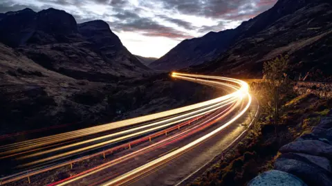 Getty Images Light trails left by a vehicle in the night on a road in the Highlands.