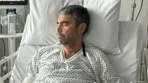 Alberto Almeida asleep in a hospital bed