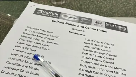 Vikki Irwin/BBC A council document is pictured with a pen. The document is for the Suffolk police and crime panel and has a list of the names of people on the panel in it. 