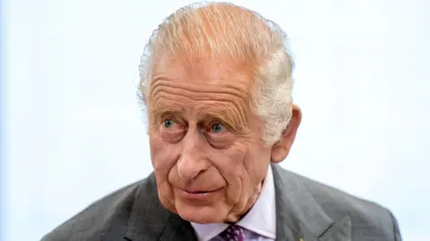 PA Media King Charles III looks off camera. He is wearing a shirt and tie and a dark coloured jacket over the top.