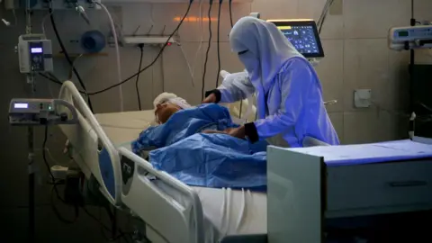 A Palestinian medic cares for injured people receiving treatment at Nasser hospital, Khan Younis, southern Gaza (9 July 2025)