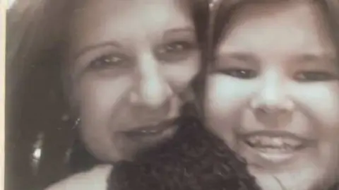 Jayne Reynolds A black and white photo of a woman with her daughter. They are embracing.