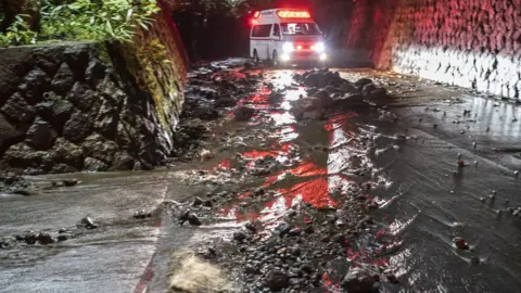 EPA An emergency vehicle drives through debris on a flooded road during the evacuation of guests at the Osen Sanso Nakamura hotel in Sengokuhara, in Nakone province, Japan, 12 October 2019.