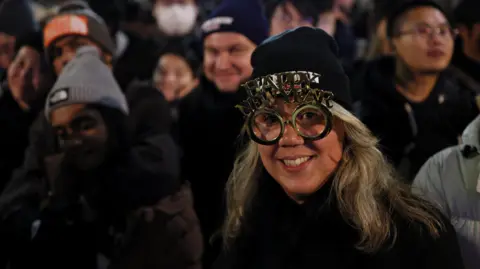 Reuters A woman is pictured in novelty glasses that read 'Happy New Year' as she stands on London's embankment