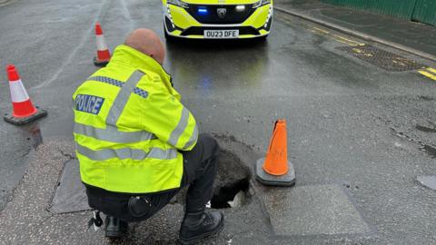 Policeman looking into a sinkhole