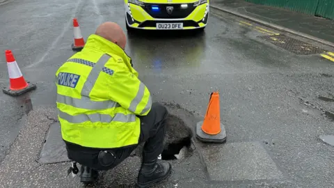 Cambridgeshire Constabulary Policeman looking into a sinkhole