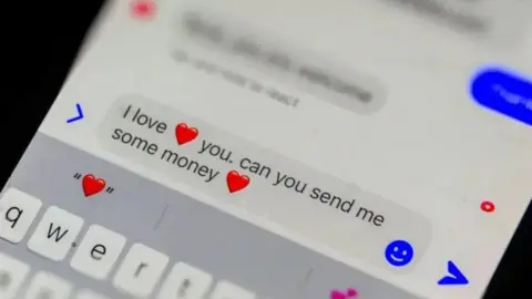 Getty Images A text message with heart emojis on an iPhone reads: "I love you. can you send me some money"