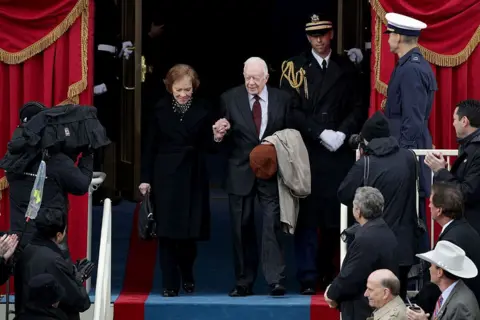 Getty Images Ish-presidenti Jimmy Carter dhe gruaja Rosalynn Carter mbërrijnë në Frontin Perëndimor të Kapitolit të SHBA më 20 janar 2017 në Uashington, DC. Në ceremoninë e inaugurimit të sotëm Donald J. Trump bëhet presidenti i 45-të i Shteteve të Bashkuara.