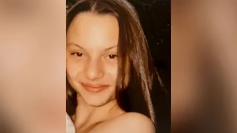 Met Police Sheryl Wilkins smiling at the camera, her shoulder is bare and she has dark brown hair and brown eyes. 