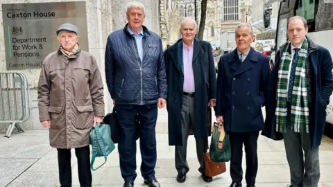 The delegation: from left to right - John Benson, Richard Nicoll, Terry Monk, Phil Jones and South Wales Central Senedd member Rhys ab Owen standing outside the Department for Work and Pensions building in central London.