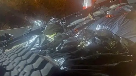 National Highways A large collection of rubbish, tyres, waste and black bags in a pile. It is night-time.