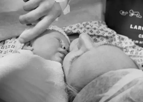 Francis Sanders Naomi cradling Easter after her birth. It's a black and white close up shot of their heads.