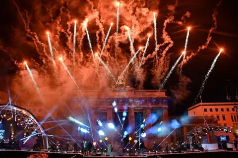Getty Images Fireworks explode over Berlin's landmark Brandenburg Gate to usher in the new year during a concert 'Willkommen 2021' (Welcome 2021)