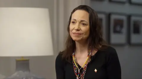 María Corina Machado looks at a person off-camera and smiles