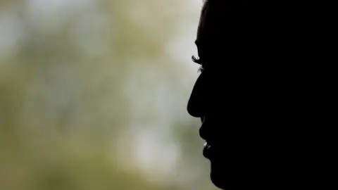 A generic image of the side profile of a woman's face. In the background you can see greenery. You can only see the side of her face as it is blacked out. 