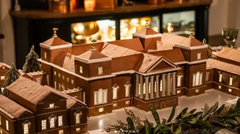 Emily Garland A gingerbread replica of an 18th Century Palladian-style country house. The gingerbread building has been topped off with icing and white edible beading to carve out the windows and other detailing.