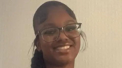 PA Media A close-up for a smiling Elianne Andam, she has agelong  achromatic  hairsbreadth  successful  a braid and is wearing glasses. She is wearing a striped schoolhouse  azygous   blouse.