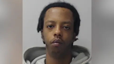 Victor Kihu looking at the camera in a police mugshot.