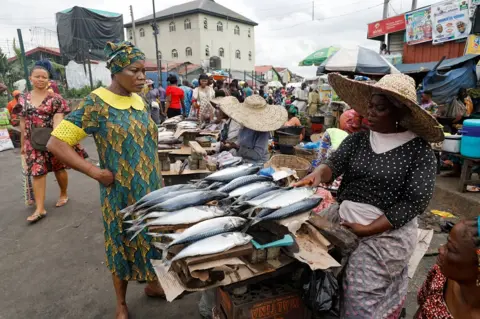 Reuters A customer speaks with a fish seller at Mile 12 International Food market in Lagos, Nigeria May 13, 2022