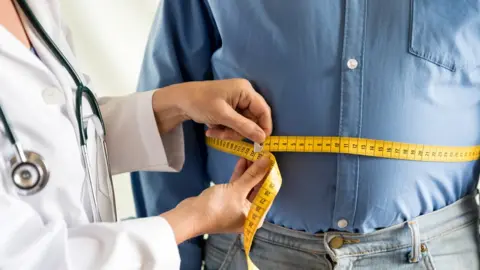 Getty Images A doctor taking a man's measurements