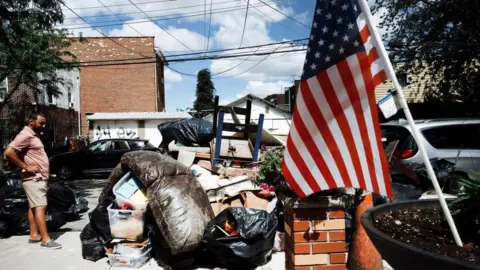 Getty Images A person sorts through belongings from their flooded home in a Queens neighbourhood.
