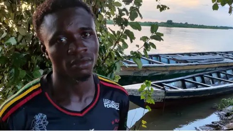 BBC/ Ahmed Ambali Mohammed Alhassan at the river bank in front of canoes