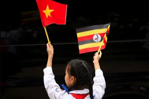 EPA A little girl waves flags of Vietnam and Uganda during a welcome ceremony at the Presidential Palace in Hanoi, Vietnam, 24 November 2022