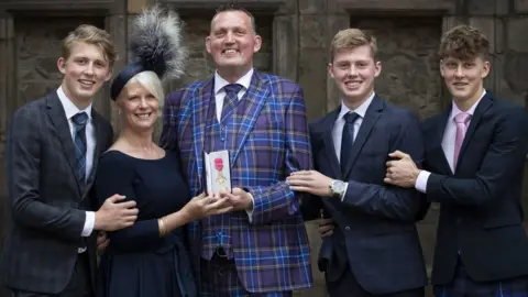 Getty Images Doddie with his family after receiving his OBE