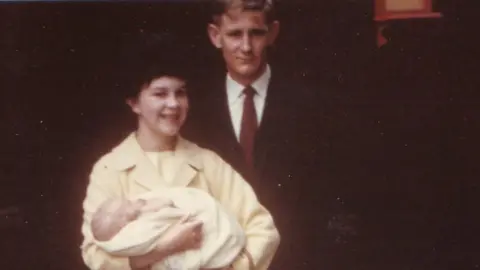 Judith Gates A young couple hold a baby