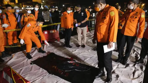 EPA Indonesian search and rescue officers inspect a bag with wreckage believed to be of the missing Sriwijaya Air plane, at Tanjung Priok port in Jakarta, Indonesia, 10 January 2021