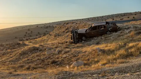 Getty Images A destroyed car left behind by fleeing Yazidis while they were escaping an IS invasion on 3 August 2014 (2016 picture)