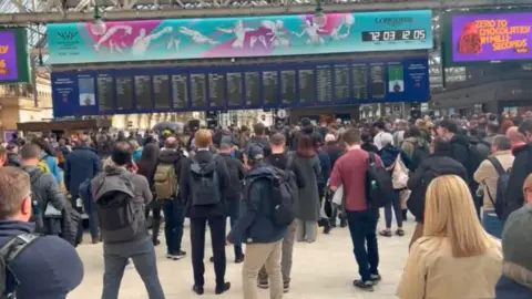 Dozens of commuters wait in the concourse at Glasgow Central