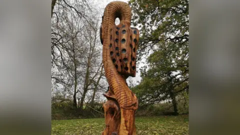 The wooden sculpture depicting a snake's head fritillary.