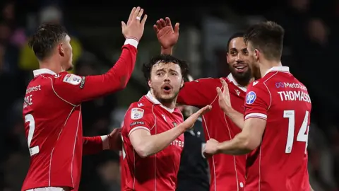 Ollie Rathbone (centre) celebrates with Wrexham team-mates 