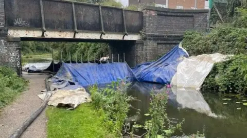 BBC Blue and white sheeting blocking off the canal underneath a bridge in Walsall