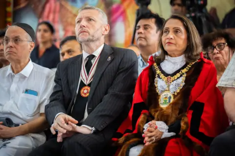 PA Media Simon Ovens and Mayor of Harrow, Anjana Patel sitting next to each other at multi-faith vigil at the Siddhashram Shakti Centre in Harrow, London, for the victims of the Air India crash on Saturday 14 June.