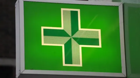A close-up image shows the green cross sign, synonymous with pharmacies nationwide.