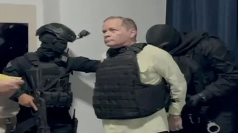 Reuters  Venezuela opposition politician Juan Pablo Guanipa, wearing a bulletproof vest, looks on as he is handcuffed after being detained by Venezuelan law enforcement officers in 2025.