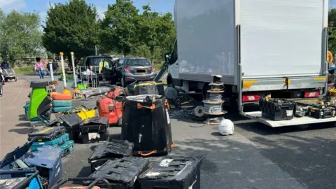 TVP Rural Crime Taskforce Power tools besides a van, which was recovered as part of TVP Rural Crime Taskforce action. Some people can be seen walking by.